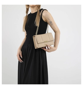 Close-up of beige leather crossbody bag featuring vertical stitching and gold chain strap