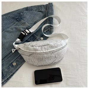 Detail of white bubble textured crossbody bag with fabric strap and plastic buckle