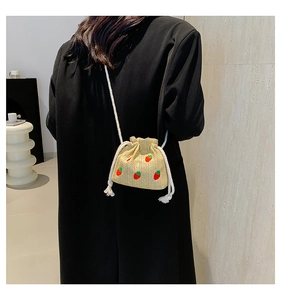 Detail of a mini straw bucket bag with red strawberry embroidery and drawstring closure