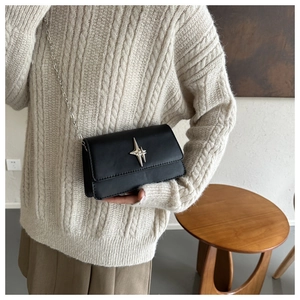 Détail du sac bandoulière en cuir noir avec boucle étoile argentée et bandoulière chaîne