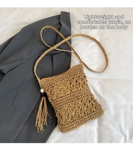 Detail of bohemian straw crossbody bag with intricate hollow pattern and tassel charm