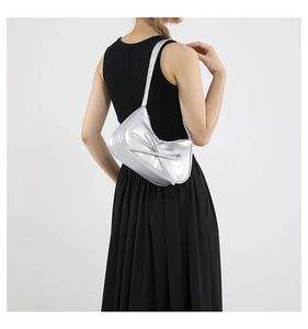 Détail d'un sac argenté métallisé avec décoration en nœud et finition lisse