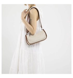 Detail of straw patchwork bag with brown leather trim and metal rivet shoulder strap