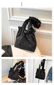 Detail view of black ballet-style tote bag with rhinestone accents and ruffled handles