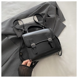 Close-up of the black PU leather backpack with vintage metal buckles and lychee texture