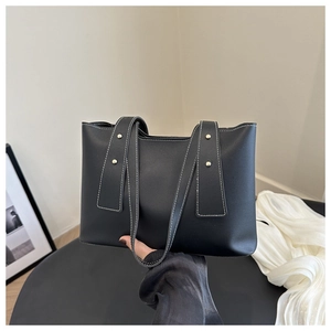 Detailed view of black square tote with white contrast stitching and gold rivets