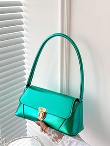 Detail of green glossy leather square bag with gold metal lock and elegant stitching