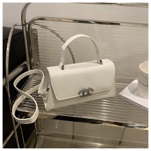 Detail of white leather handbag showing crocodile texture and silver metal hardware accents