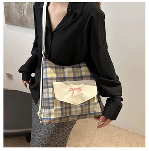 Detail of plaid crossbody bag with a cute bow embroidery on the front flap pocket