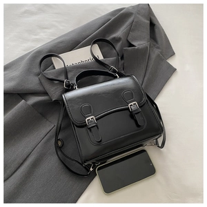 Detail of black vintage PU leather backpack featuring silver buckles and glossy finish