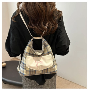 Detail of plaid backpack featuring a white front pocket with a pink bow decoration