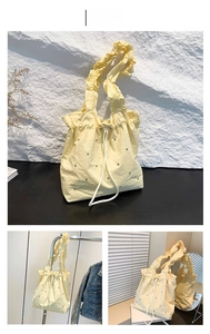 Detail of yellow drawstring tote bag with ruffle strap and mini metal accents