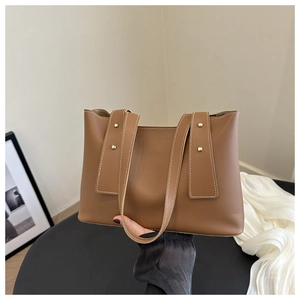 Detailed view of brown PU leather tote bag with white contrast stitching and gold rivets