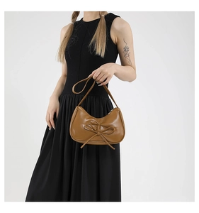 Détail d'un sac demi-lune marron en cuir PU avec un nœud élégant et une bandoulière fine