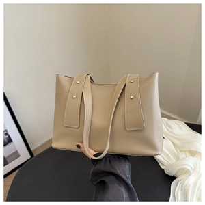Detail view of khaki leather tote bag with four decorative metal rivets and sturdy handles