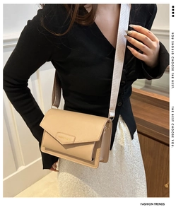 Beige envelope crossbody bag with wide strap and fashion logo shown on model