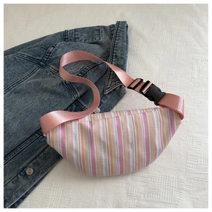 Détail d'un sac de poitrine à rayures roses et blanches posé sur une veste en jean