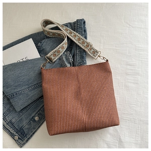 Detail of brown woven bucket bag featuring wide geometric ethnic style fabric strap