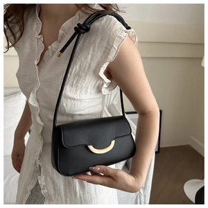 Detail of black leather shoulder bag featuring gold hardware and knotted strap accents