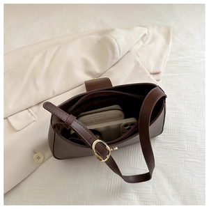 Detail of dark brown leather baguette bag showing spacious interior with golden hardware
