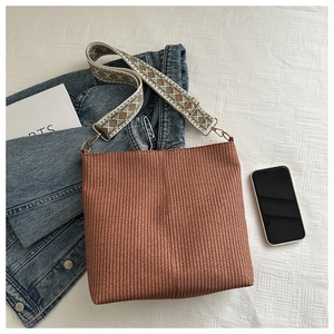 Detail of hand-woven brown tote bag featuring a wide bohemian style jacquard strap