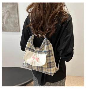 Detail of plaid backpack showing pink bow decoration and white leather pocket