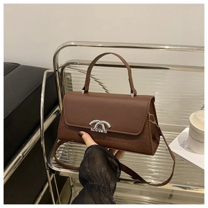 Detail of brown faux leather handbag featuring crocodile pattern and silver metal clasp