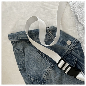 Detail of white nylon strap with black plastic buckle on denim jacket background