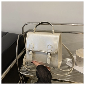 Detailed view of a cream-white mini backpack with metallic buckles and faux leather texture