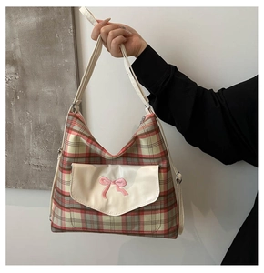 Close-up of red and green plaid canvas tote bag with pink bow embroidery on white pocket