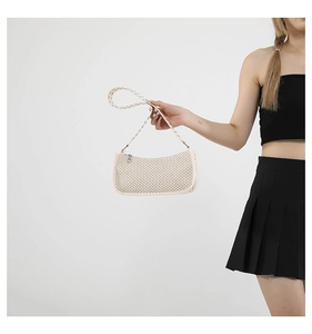 Close-up of cream woven shoulder bag with diamond pattern and cutout strap detail