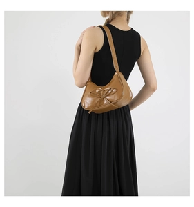 Détail d'un sac à bandoulière marron plissé style ballet avec élégant nœud décoratif