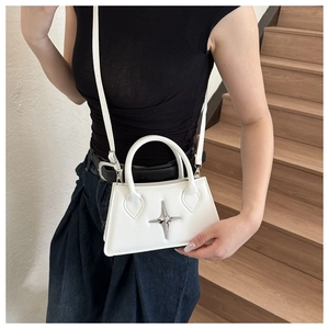Détail d'un sac bandoulière en similicuir blanc avec emblème d'étoile en métal argenté