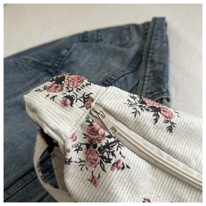 Gros plan du sac en velours côtelé fleuri avec roses roses et fermeture éclair en métal
