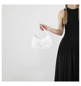 Détail du sac à bandoulière blanc plissé avec nœud délicat et fine poignée élégante