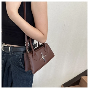 Détail d'un sac carré marron foncé avec rivet étoile argenté et bandoulière en cuir