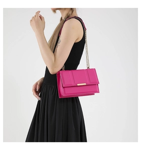 Detail of fuchsia quilted crossbody bag with gold metal chain strap on model