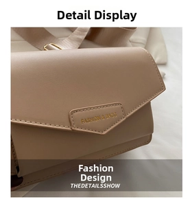Detail of beige leather bag with envelope flap, gold lettering and wide fabric strap