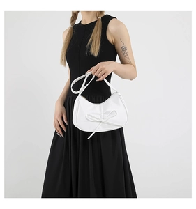 Détail du sac à bandoulière blanc en demi-lune avec nœud et texture en cuir lisse