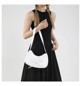 Détail d'un sac à bandoulière blanc en similicuir avec un nœud décoratif en relief 3D