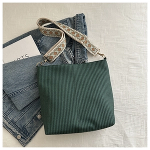 Detail of dark green woven tote bag with adjustable geometric patterned wide shoulder strap