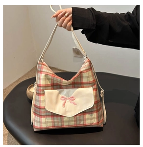 Close-up of red and pink plaid tote bag featuring a white pocket with bow embroidery