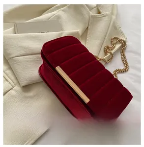 Close-up of quilted burgundy velvet texture and elegant gold metal chain on small bag