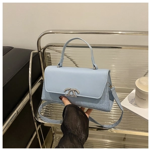 Detail of baby blue handbag with mixed leather textures and silver metal buckle