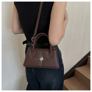Petit sac carré marron foncé avec boucle étoile argentée porté à l'épaule par un mannequin