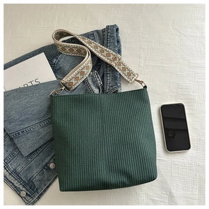 Detail of dark green bucket bag with corduroy texture and boho patterned wide strap