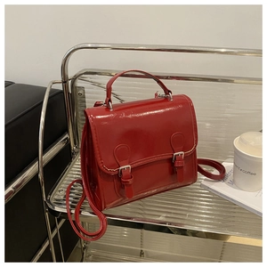 Macro view of red patent leather satchel with silver buckles and neat stitching details