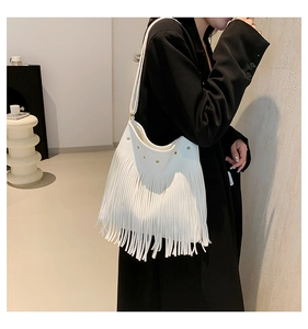 Detail of white fringe shoulder bag with golden studs and bohemian tassel texture