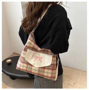 Detail of vintage plaid tote bag featuring a white pocket with pink bow embroidery