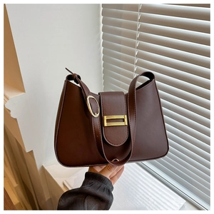Detail of deep brown leather baguette bag with a premium gold square buckle and stitching